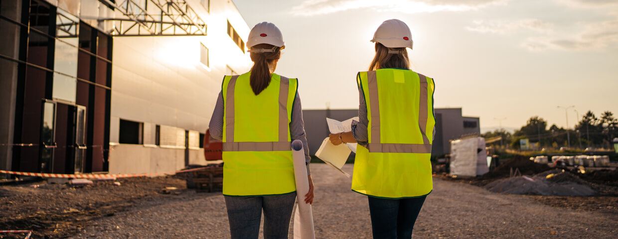 Two female construction workers walking towards sunset